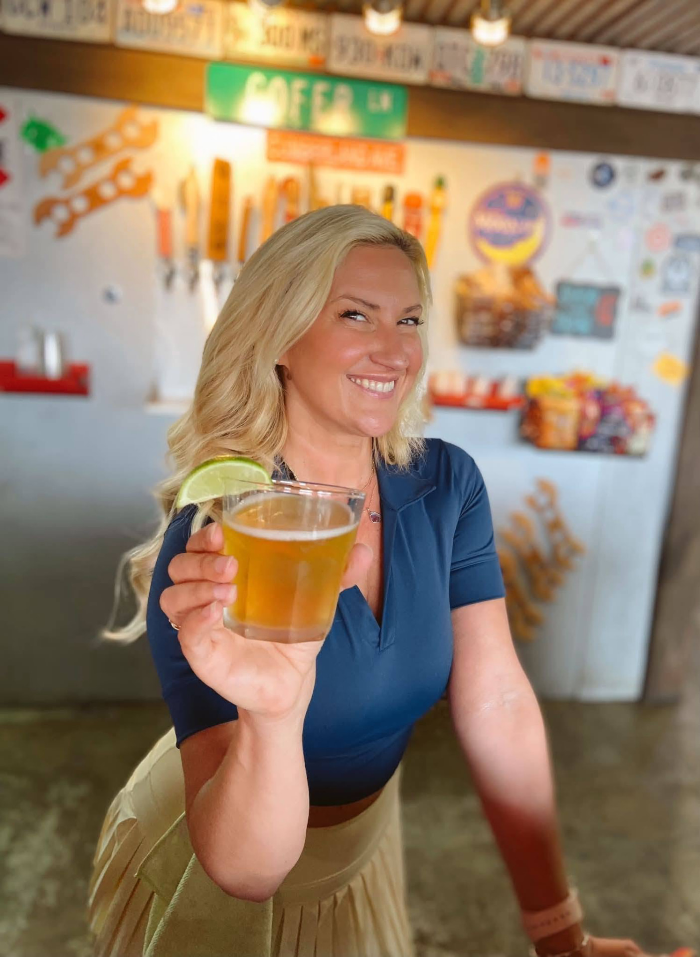A bartender at Cofer's Garage holding up a beer with a lime wedge in front of the tap wall