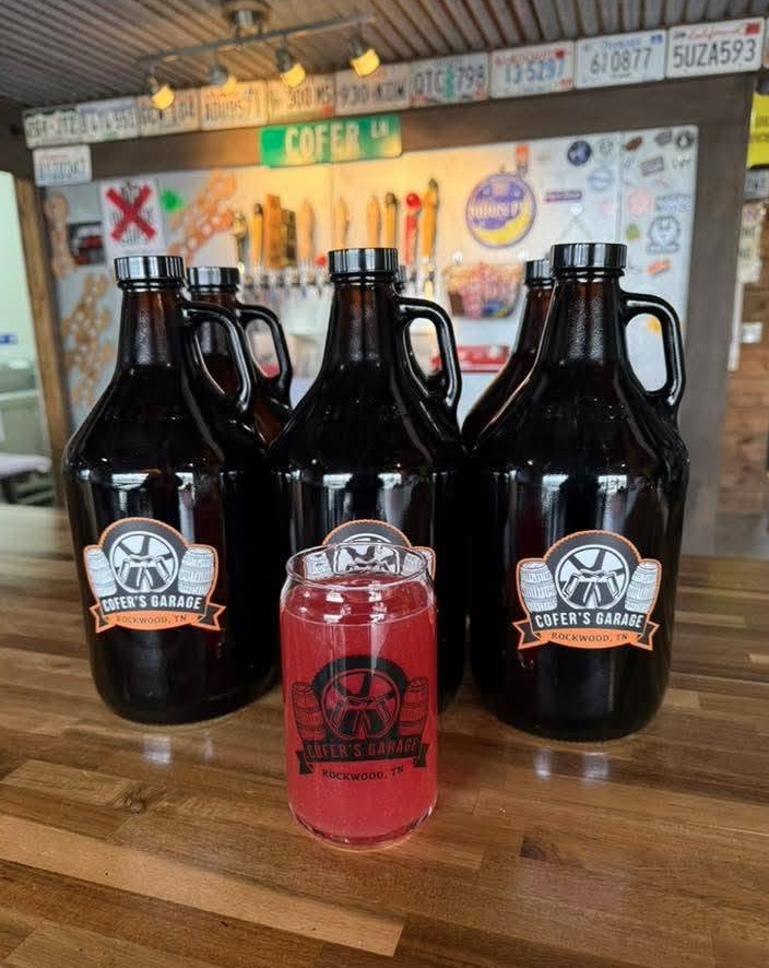 Cofer's Garage growlers and a glass of red beer in front of the tap wall